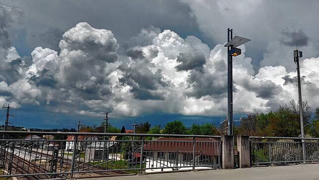 Auch auf der Bahnhofsbrücke ist die Beleuchtung zur Mittagszeit an. Im Hintergrund braut sich ein Gewitter zusammen.