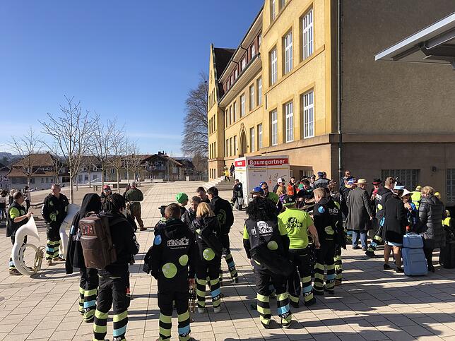 Guggenmusiker des Fröscheloch-Echos tanken vor Beginn der Verhandlung in der alten Schulturnhalle noch etwas Sonne im Freien.