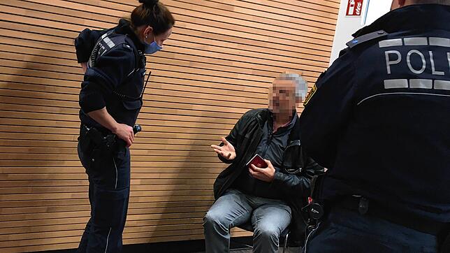 Zwei Polizisten nehmen die Personalien des Masken-Muffels auf.