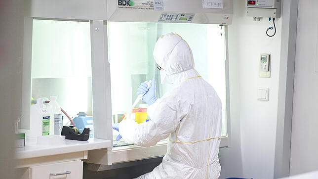Ein Mitarbeiter des Labors Dr. Blessing in Singen bereitet unter der Sicherheitswerkbank ein Probenröhrchen für die Virus-Inaktivierung vor.