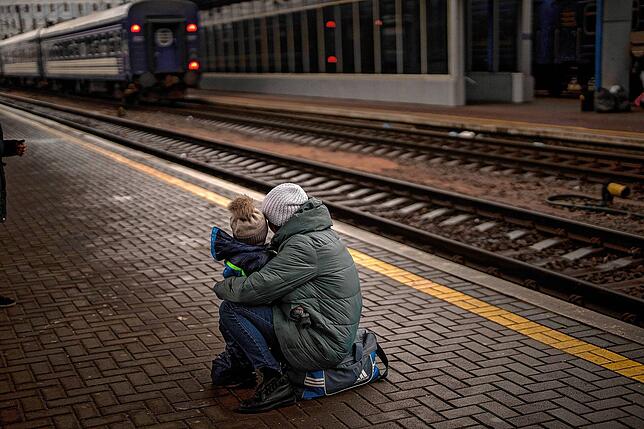 Eine Frau und ihr Kind schauen auf einen abfahrenden Zug, als sie am Bahnhof von Kiew in der Ukraine zu fliehen versuchen. Während ...