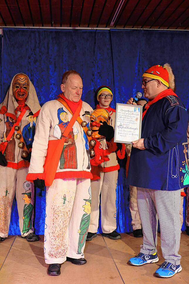 Für sein 25-jähriges Engagement um die Göschweiler Fastnacht wird Ortsvorsteher Manfred Furtwängler (links) ins Hanselehäs gesteckt und ...