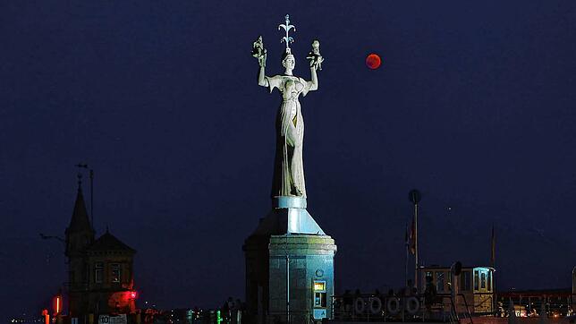 Die Imperia, das Konstanzer Wahrzeichen im Hafen, wird nachts angeleuchtet.