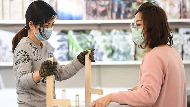 Zwei Frauen mit Mundschutz sind am Stand eines chinesischen Unternehmens auf der Konsumgütermesse Ambiente in Frankfurt mit ...