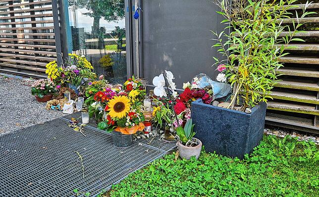 Blumen und Kerzen stehen vor dem Seegarten. Das Polizeisiegel an der Tür ist entfernt, Spuren davon sind noch zu erkennen.