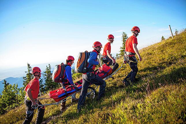 Dieses exemplarische Bild zeigt, wie eine Sommerrettung der Bergwacht mit einer besonderen Trage auf Rädern ablaufen kann.