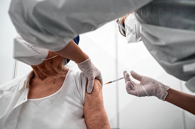 Eine Krankenschwester impft im Impfzentrum in der Paul-Horn-Arena eine alte Dame mit einem Covid-Impfstoff.