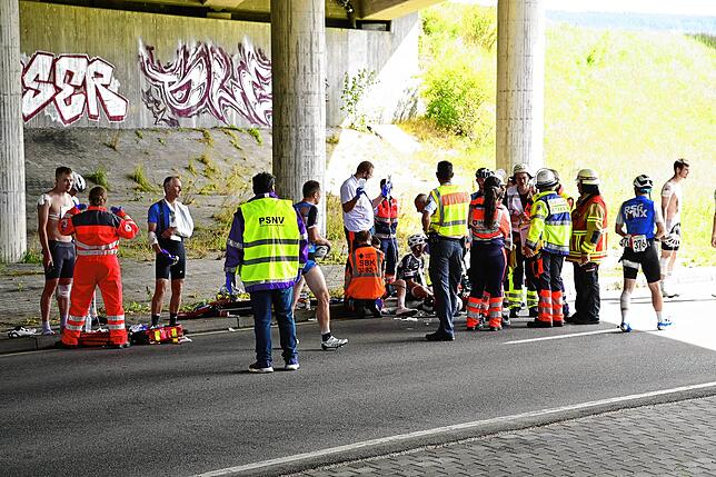Verletzte Fahrer werden im Schatten unter der Autobahnbrücke betreut.
