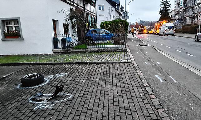Links der Reifen, den der Wagen verloren hat. Die eingezeichneten Spuren zeigen, dass er auch über den Fußweg raste, ehe er etwa 100 ...