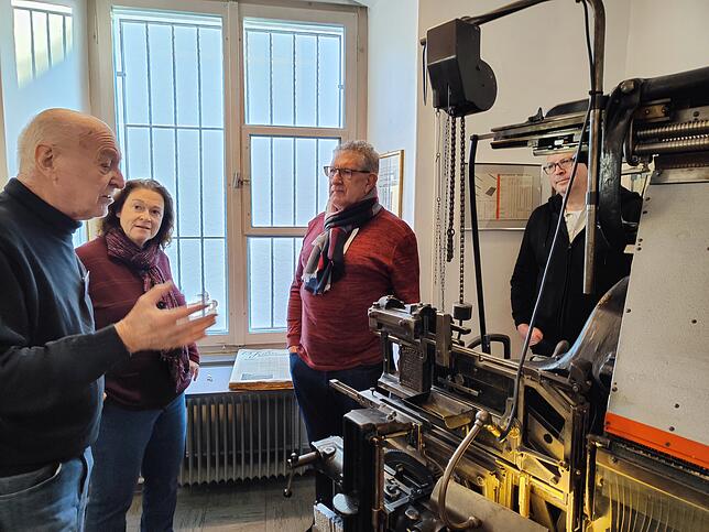 Gerhard Vogel (links) führt die Bleisetzmaschine „Linotype“ vor.