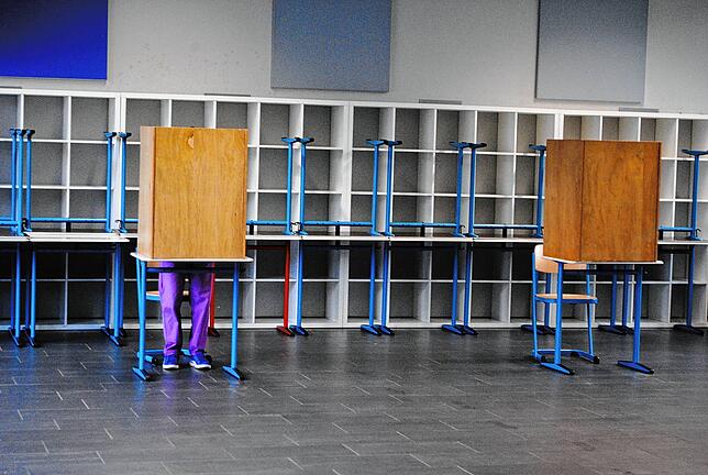 Eine Wählerin sitzt in einer der Wahlkabinen in der alten Aula des Hochrhein-Gymnasiums in Waldshut.