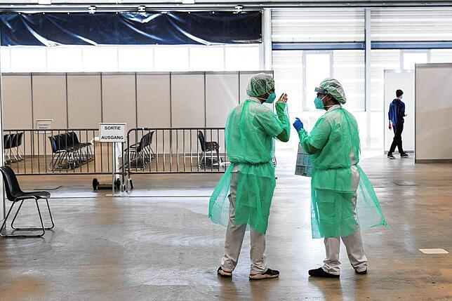 Im Schweizerischen Freiburg unterhalten sich Mitarbeiter des Gesundheitswesens in einem Testzentrum.
