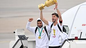 Hoch die Hände: Kapitän Atakan Karazor steigt mit dem Pokal aus dem Flugzeug.