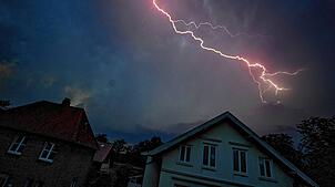 Ein Blitz zuckt während eines Gewitters über den dunklen Abendhimmel.