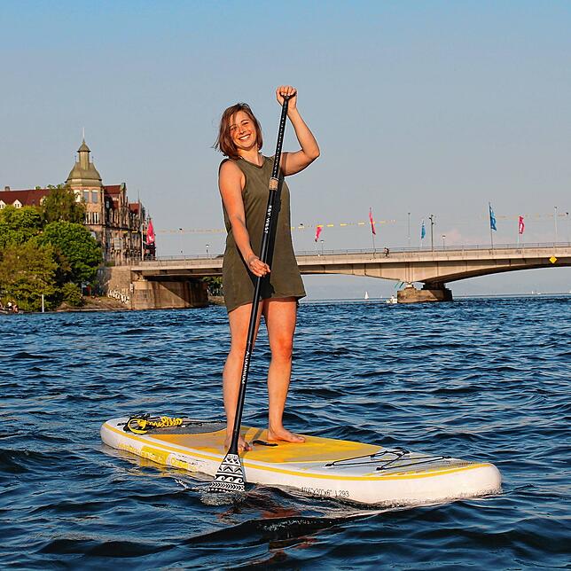 Lena Müller (31) ist am See zu Hause und lenkt ihr Stand-Up-Paddle Board geübt über den Seerhein.