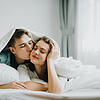 Happy young lovely couple in love kissing in bed