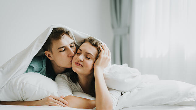 Happy young lovely couple in love kissing in bed