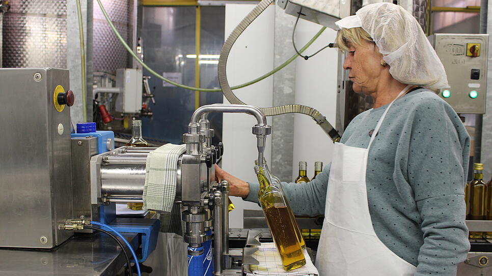 Mit goldener Farbe fließt das Rapsöl an der Abfüllmaschine in die Flasche. Der Apparat wird mit Fußschaltern von Mitarbeiterin Karola ...