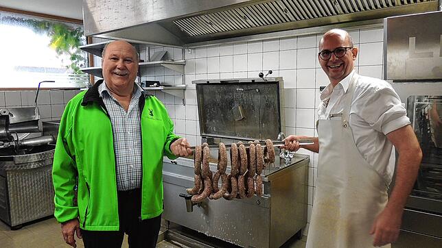 Karl und Sebastian Amann zeigen frische Bauernbratwürste, die für das Schlachtfest zubereitet wurden.