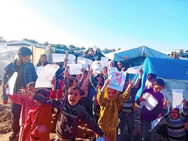 Leben in Zelten im Gazastreifen: Kinder in einem Camp in Deir Al Balah halten ihre selbstgemalten Bilder in die Luft.