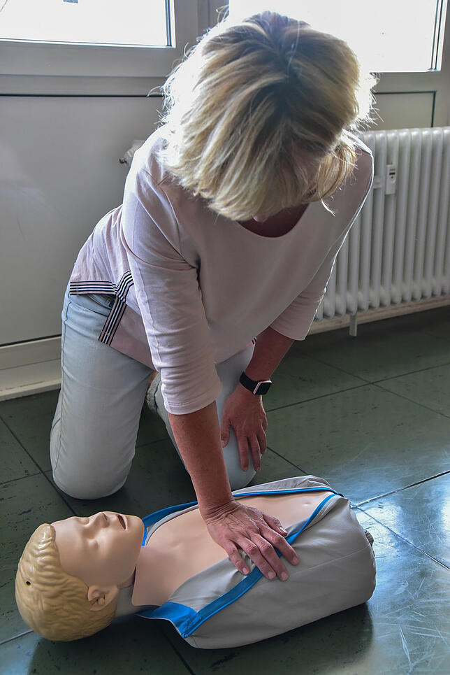 Elke Bettecken zeigt eine Herzdruckmassage an einem Kind: Mit ausgetrecktem Arm und einem Handballen wird auf den Brustkorb gedrückt. ...