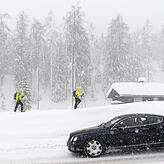 Davos ist ein beliebter Ort für Wintersportler. Auf dem Bild sind zwei Schneeschuhwanderer neben der Straße unterwegs.