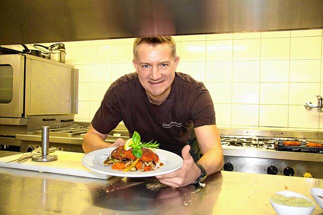 Daniel Märkl reicht ein Essen aus seiner Küche im Ziegelhofstüble.