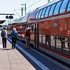 Reisende gehen neben einem Regionalexpress (RE) der Deutschen Bahn über den Bahnsteig.