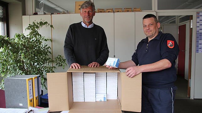 Markus Esterle und Christian Pflumm (von links) mit einer Kiste voller Lolli-Tests. Im Keller des Rathauses stapeln sich nach Wegfall ...