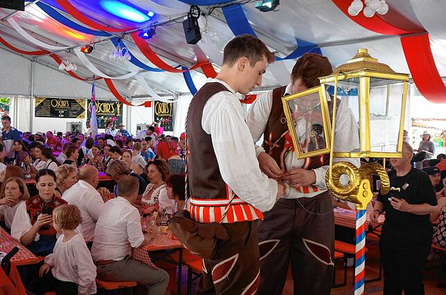 Die Vorbereitungen: Zwei Junggesellen befestigen den Faden an der Kerze und am Glas, dann wird die Kerze in der Laterne angezündet.