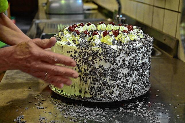 Die mit Sahne rundherum eingekleidete Torte wird zum Schluss mit Schokoraspeln bestreut.