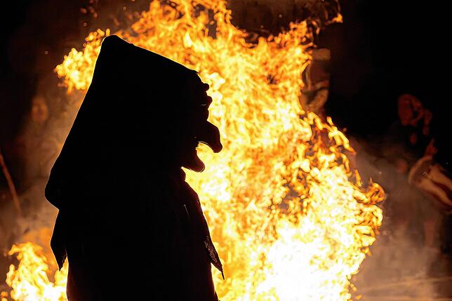 Eine Hexe vor dem Feuer, das für den Hexensprung der Tiengener Schlosshexen lodert.