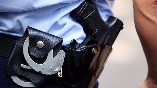 Ein Polizist trägt Handschellen und seine Dienstwaffe bei sich (Symbolbild). In Schaffhausen in der Schweiz hat die Polizei einen ...