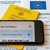 Ein Impfpass und ein Smartphone, auf dem die App CovPass läuft, liegen auf einem Impfzertifikat. (Symbolbild)