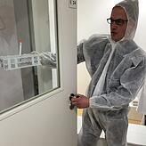 Molekularbiologe Lars Steinmüller-Magin trägt im Schutzanzug eine Probe in einem Glasröhrchen in das Hochsicherheitslabor.