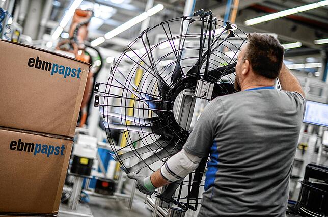 Ein Mitarbeiter des Elektromotoren- und Ventilatorenherstellers EBM-Papst, arbeitet in der Produktion an einem Ventilator. Der ...