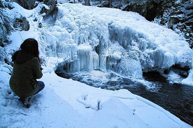 Eine Wandersfrau bestaunt den immensen Eispanzer, zu dem der Wasserfall an der Gletschermühle (auch: Krai-Woog-Gumpen) zwischen ...