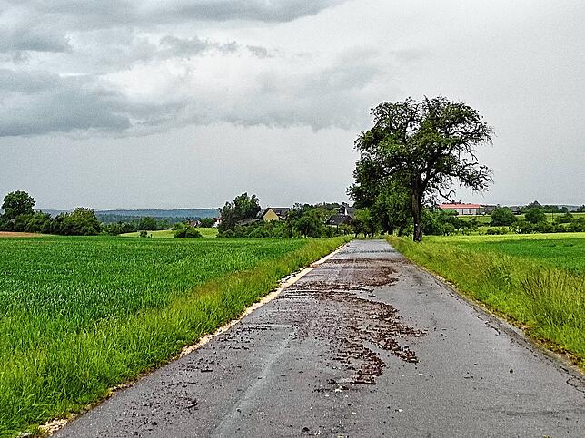Nach dem Unwetter vom 16. Mai 2024 ist auf einer Straße bei Raithaslach zu sehen, wie das Wasser Dreck auf die Fahrbahn gespült hat.