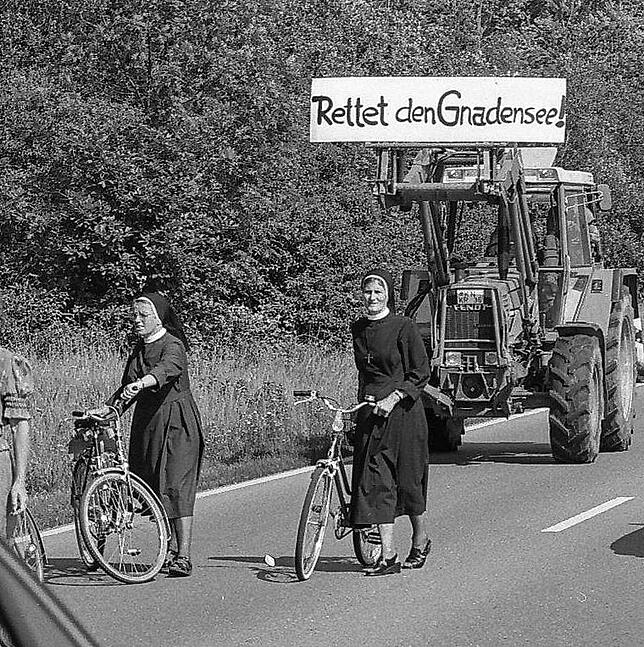„Rettet den Gnadensee!“ Im Vordergrund sind die Ordensschwestern mit ihren Fahrradrädern bei der Demo zu erkennen.