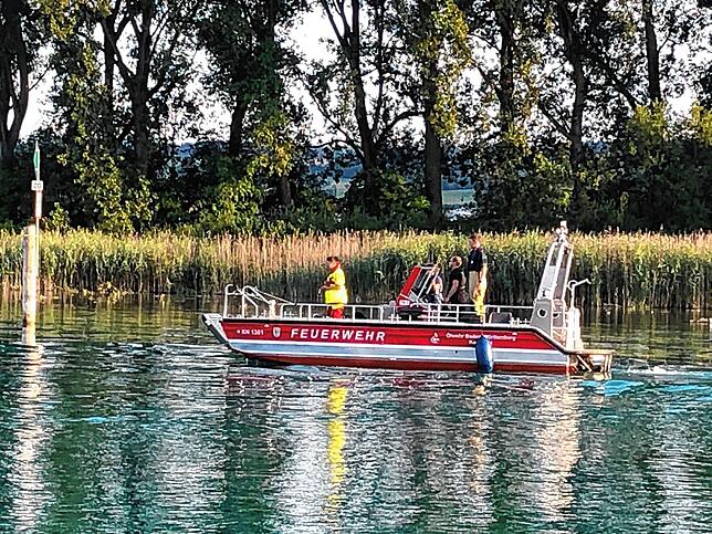 Die Besatzung eines Feuerwehrbootes sucht die Wasseroberfläche ab.