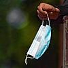 Ein Frau hält vor einem Bäckereigeschäft ihren Mundschutz in der Hand. Baden-Württemberg will die Maskenpflicht draußen abschaffen, ...