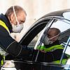 Ein Bundespolizist mit Atemmaske kontrolliert am Grenzübergang zur Schweiz ein Fahrzeug.