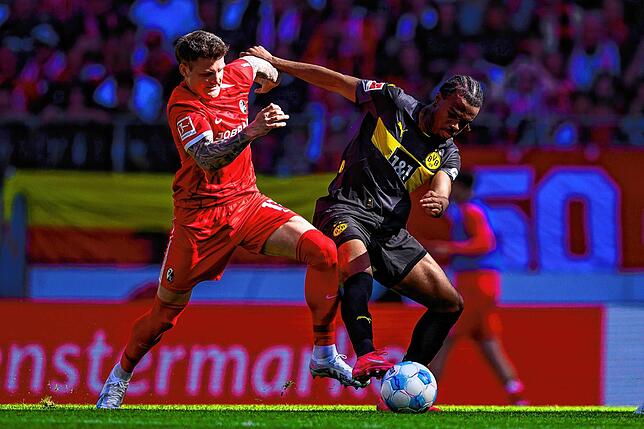 Freiburgs Lukas Kübler (l) in Aktion gegen Dortmunds Carney Chukwuemeka (r).