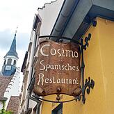 Das urige Schild des Restaurants Cosimo, im Hintergrund die Spitalkapelle.