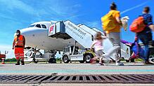 Passagiere laufen auf dem Bodensee-Airport mit Gepäck zum Flieger.
