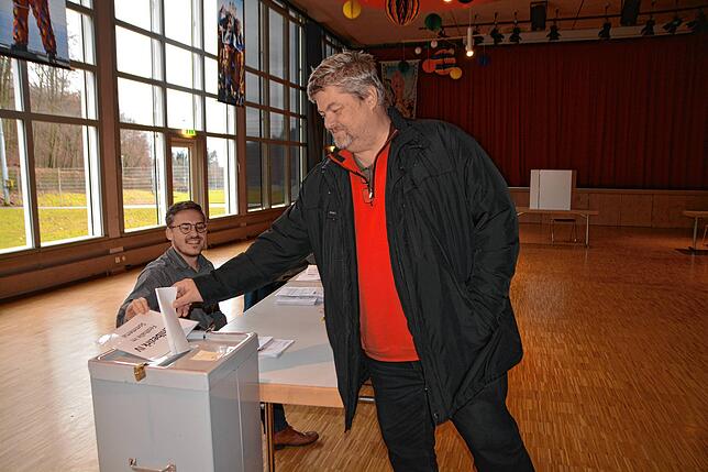 Lars Meesmann wirft in der Sommertalhalle seinen Stimmzettel zur Bundestagswahl in die Wahlurne. Links ist Wahlhelfer Markus Kremp zu sehen.