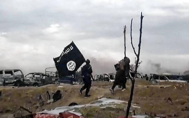 Syrien, Baghus: IS-Kämpfer laufen mit einer IS-Flagge.