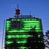 Der ehemalige Telekomturm in Petershausen leuchtet am Donnerstagabend, 8. August, grell und grün. Ein riesiges Werbebanner hängt am Gebäude.