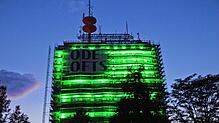 Der ehemalige Telekomturm in Petershausen leuchtet am Donnerstagabend, 8. August, grell und grün. Ein riesiges Werbebanner hängt am Gebäude.