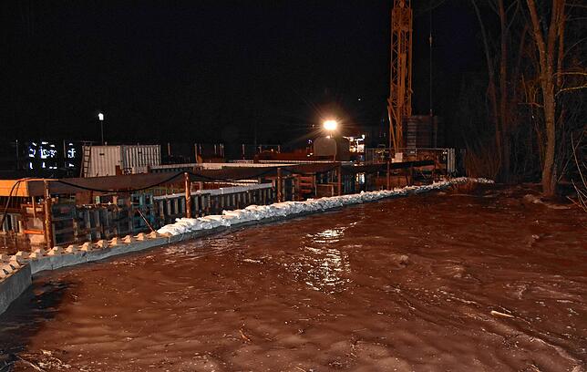 Mit Sandsäcken verstärkt die Feuerwehr den vorhandenen Betonwall entlang der Baustelle.